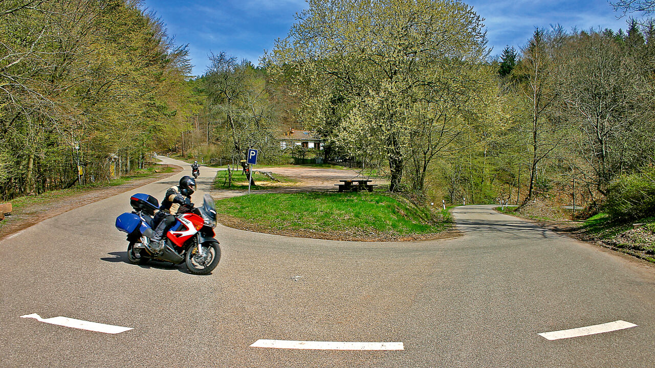 Motorrad in einer Kehre auf einer Waldstraße mit Frühlingsgrün